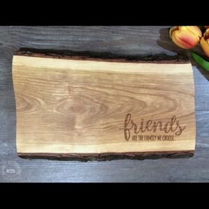 Live edge board with "friends are the family we choose" engraved in the corner.