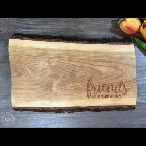 Live edge board with "friends are the family we choose" engraved in the corner.