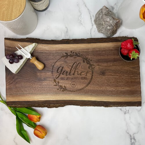 Live edge charcuterie board with the gather design engraved in the center.