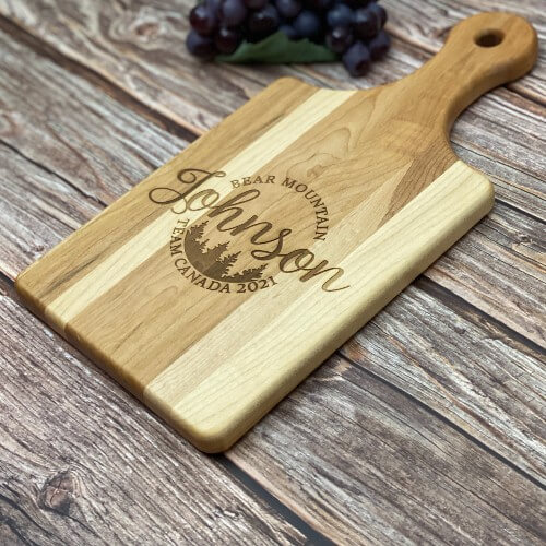 Engraved cutting board with the last name in the center, surrounded by custom text.