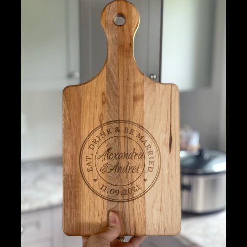 Paddle style cutting board with the Tuscan eat, drink and be married design engraved in the center.