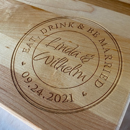 Close up of the Tuscan eat, drink and be married design engraved in the corner of a cutting board.