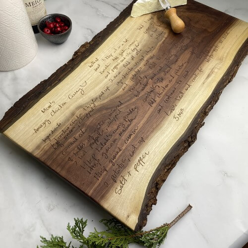 A solid wood charcuterie board with a handwritten recipe engraved.
